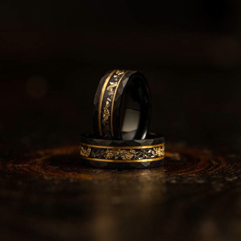 Unisex wolfram ring met gouden blad en zwarte meteoriet gedragen aan de vinger; stijlvol accessoire.