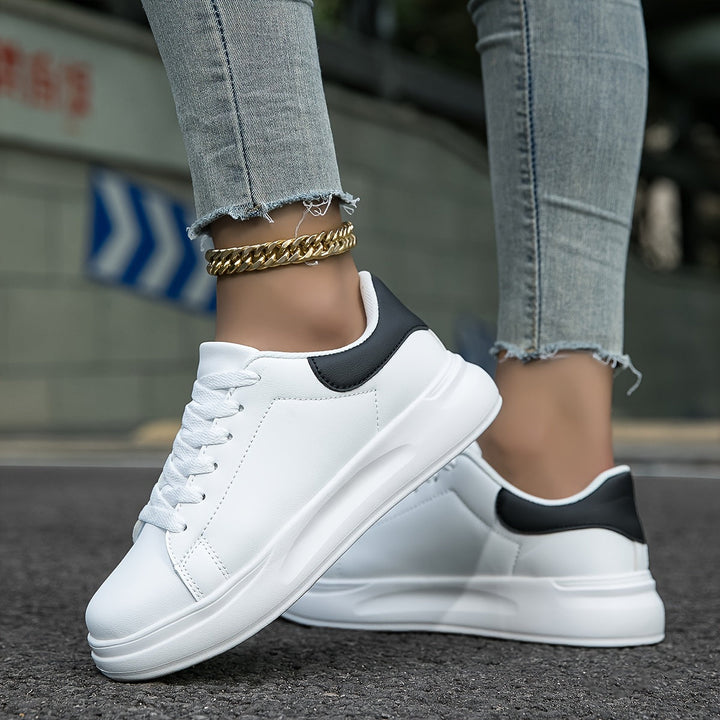Witte dames leren sneakers, stijlvol en orthopedisch, close-up van de zijaanzicht met veters en rubberen zool.