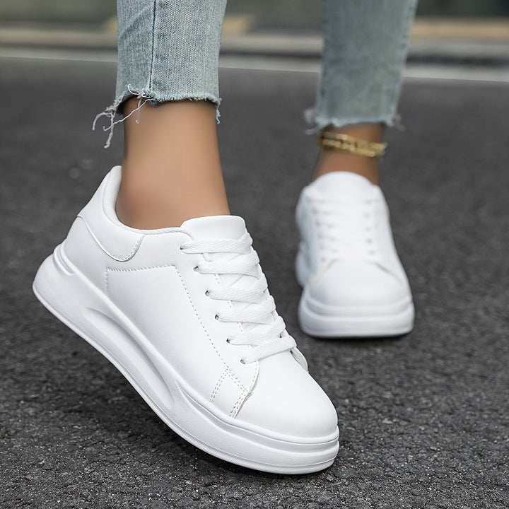 Witte dames leren sneakers, stijlvol en orthopedisch, close-up van de zijaanzicht met veters en rubberen zool.