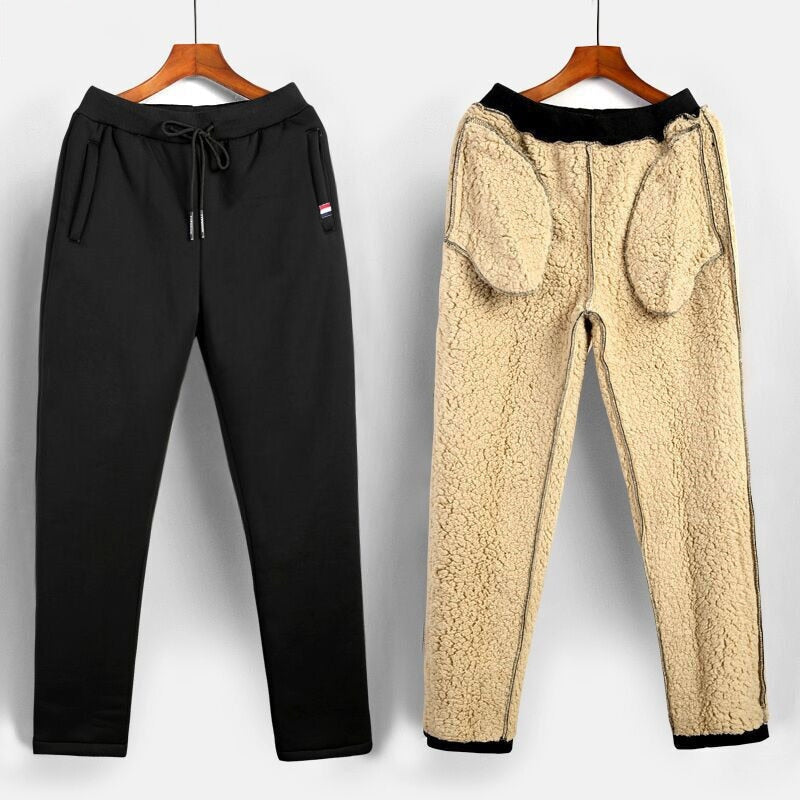 Stapel zwarte en grijze heren thermobroeken. Warme fleecebroek voor winterkleding, sportbroek en casual comfort.
