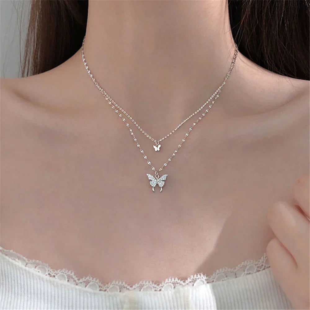 Duo-laags zilveren ketting met vlinderhanger en sprankelende zirkoniastenen, elegant en natuur-geïnspireerd sieraadontwerp.