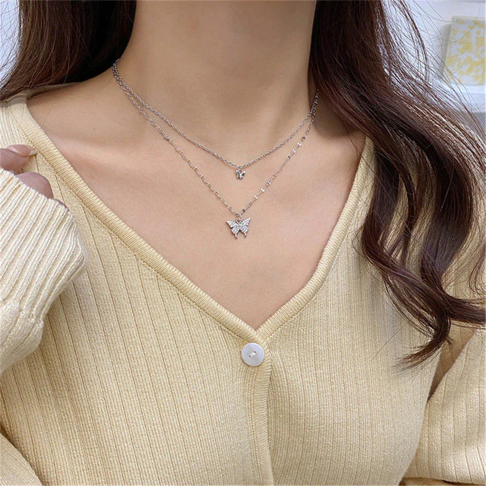 Duo-laags zilveren ketting met vlinderhanger en sprankelende zirkoniastenen, elegant en natuur-geïnspireerd sieraadontwerp.