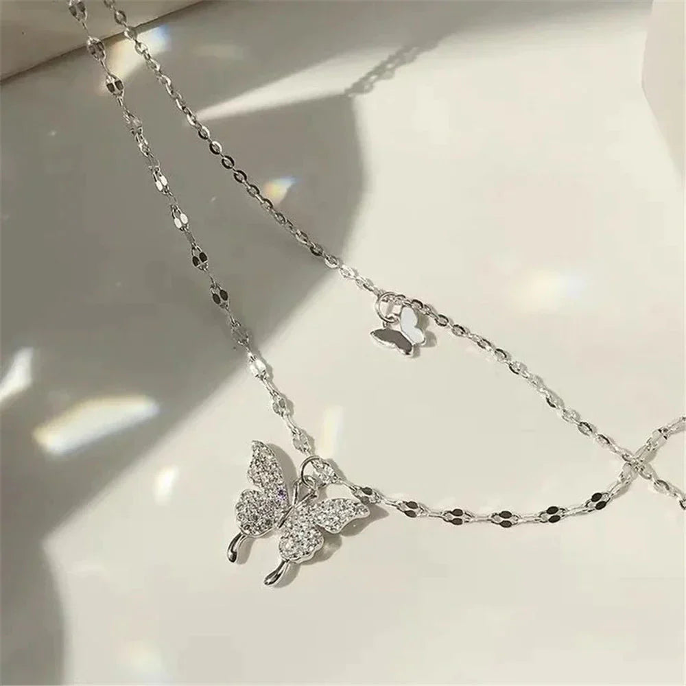 Duo-laags zilveren ketting met vlinderhanger en sprankelende zirkoniastenen, elegant en natuur-geïnspireerd sieraadontwerp.