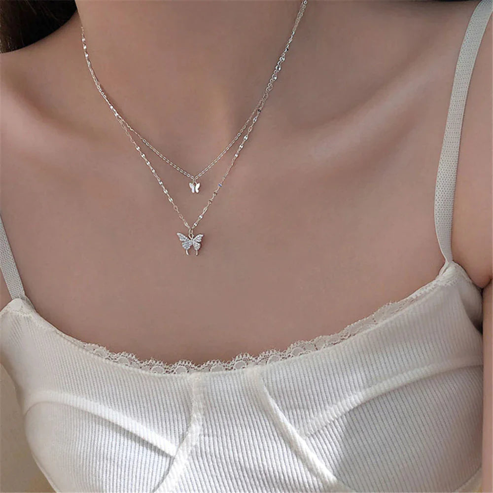 Duo-laags zilveren ketting met vlinderhanger en sprankelende zirkoniastenen, elegant en natuur-geïnspireerd sieraadontwerp.