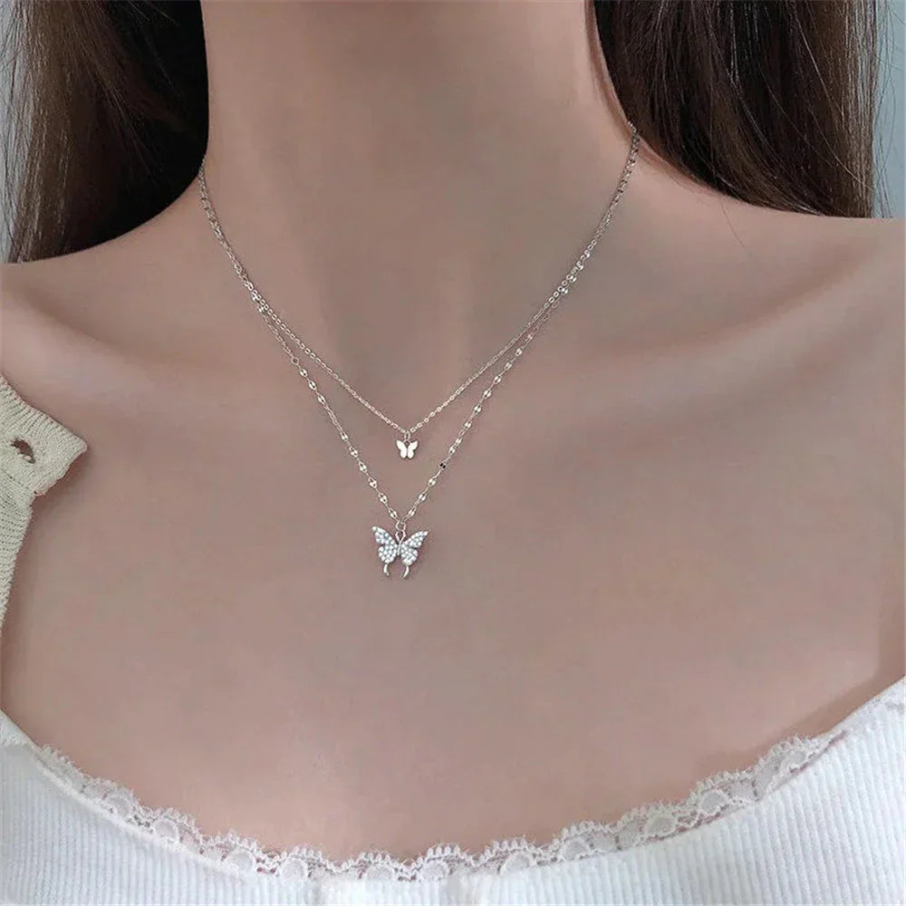Duo-laags zilveren ketting met vlinderhanger en sprankelende zirkoniastenen, elegant en natuur-geïnspireerd sieraadontwerp.